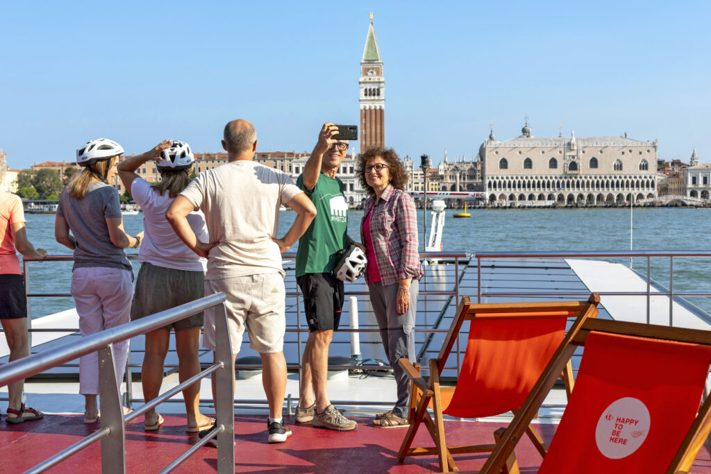 Venezia, viaggi in barca e bici, persone che godono della vista di San Marco dal ponte di una nave